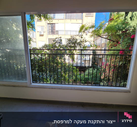 חלון גדול עם מסגרת מתכת ונוף ירוק